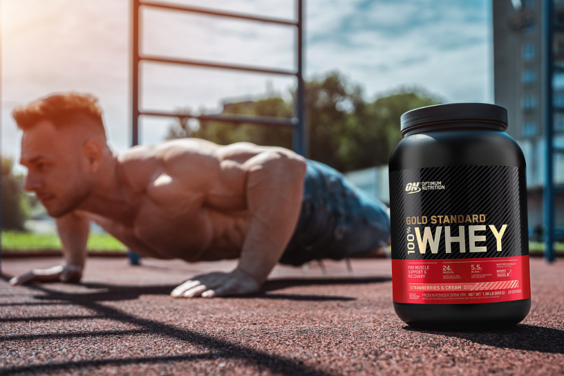 Man doing push-up next to container of protein powder